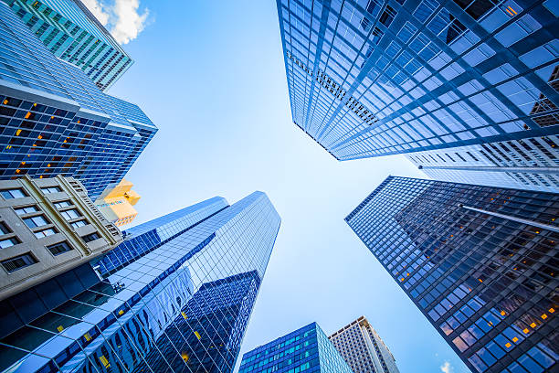 Moderne Hochhäuser mit Glasfassaden ragen in den blauen Himmel. Der Blick von unten betont die imposante Architektur und den urbanen Lebensstil. Perfekt für Themen wie Stadtentwicklung, Architektur und modernes Design.
